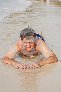 man in bathingsuit is lying at the beach and enjoying the saltwater