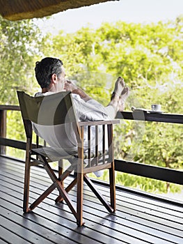 Man In Bathrobe Sitting In Terrace With Feet Up photo