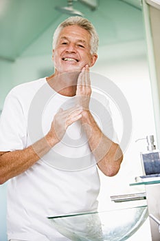 Man in bathroom applying aftershave