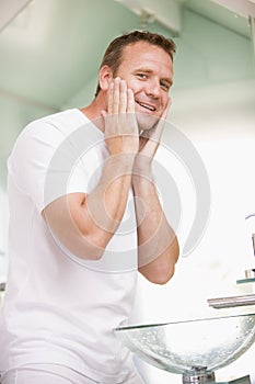 Man in bathroom applying aftershave