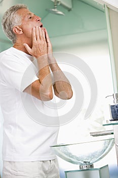 Man in bathroom applying aftershave and smiling photo