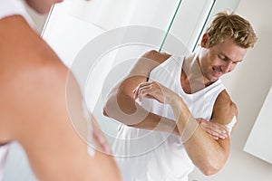 Man in bathroom applying lotion