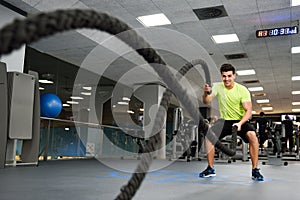 Man with battle ropes exercise in the fitness gym.