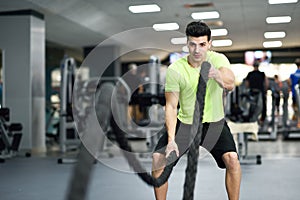 Man with battle ropes exercise in the fitness gym.