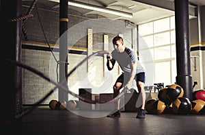 Man with battle ropes in gym