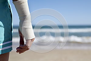 Man on the beach with a bandage in his wrist
