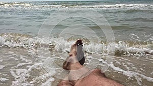 A man on the beach basking in the surf enjoys the sound of the ocean and rolling waves on the sandy beach