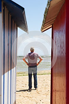 Man on the beach in front of beach huts photo