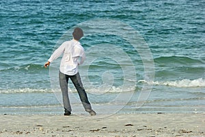 Man on beach throwing rocks into sea