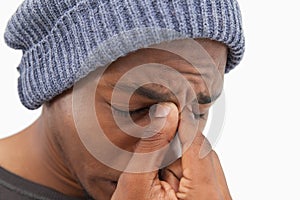 Man in beanie hat wincing with a headache photo