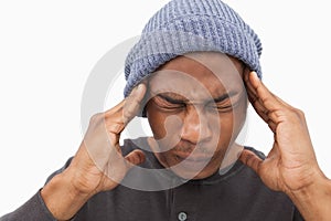 Man in beanie hat wincing with pain of headache photo