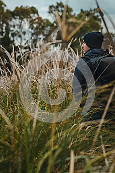 Man with beanie walking in the middle of the rushes on wild environment. Vertical photography