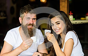 Man with beard and attractive happy smiling girl hold hands drinking coffee. Couple happy spend time in cafe. Enjoy