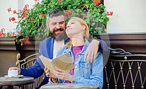 Man with beard and blonde woman cuddle on romantic date. Romance concept. Couple flirting romantic date read book. Love