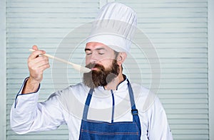 Man with beard in cook hat and apron hold cooking tools. Cooking as professional occupation. Hipster bearded chef hold