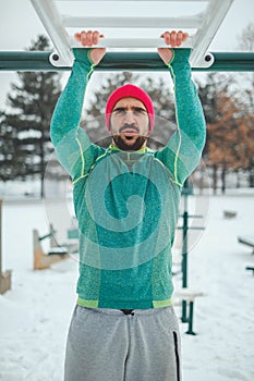 Man doing overhand chin ups outside on a snowy day photo