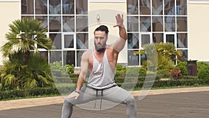Man with beard doing squats training outdoors showing power and strength.