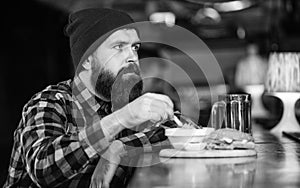 Man with beard eat burger menu. Brutal hipster bearded man sit at bar counter. Cheat meal. High calorie food. Delicious