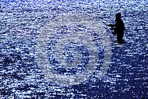 Man with Beard Flyfishing Fly Fishing in River Silhouette with Sunlight