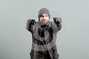 Man with beard gesturing with forefingers wearing cap and gloves photo