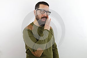 Man with beard and glasses wearing casual clothes hand on mouth telling secret rumor