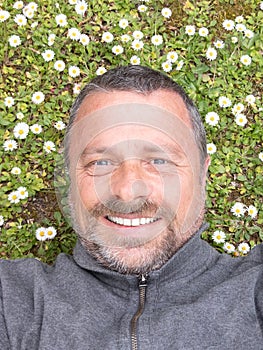 Man with beard in green meadow background Guy taking selfie photo on smiling face lying on grass