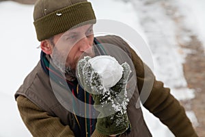 Man with beard in hat throwing snowballs in yard