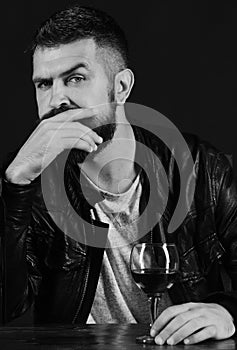 Man with beard holds glass of wine on brown background.