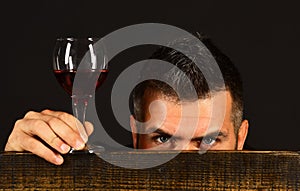 Man with beard holds glass of wine on brown background