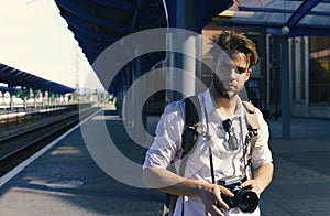 Man with beard holds photocamera on station background. Urban photo and travelling concept. Tourist ready to take