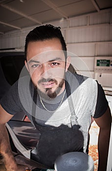 Man with beard holds polising tool in the hands in car service