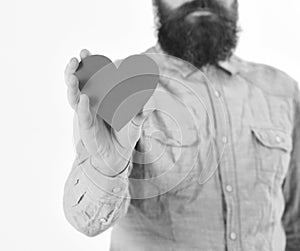 Man with beard holds red paper heart in hand, defocused.