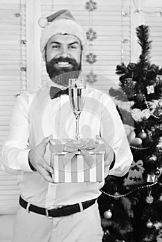 Man with beard holds striped present box with champagne glass
