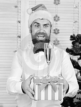 Man with beard holds striped present box with champagne glass.