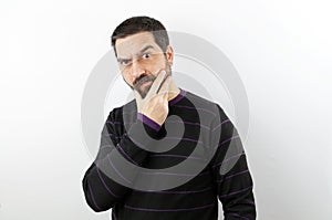 Man with beard isolated on white background, angry and worried touching his chin.
