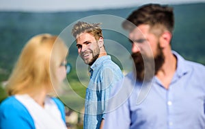Man with beard jealous aggressive because girlfriend interested in handsome passerby. Jealous concept. Passerby smiling
