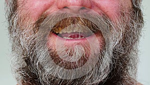Man with beard laughing. A man with a gray brown beard laughs emotionally, strokes his mustache