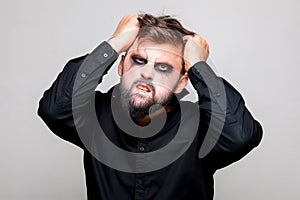 man with a beard and makeup for Halloween grabbed his hair with his hands