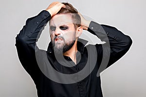 man with a beard and makeup for Halloween grabbed his hair with his hands