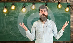 Man with beard and mustache on confused face stand in front of chalkboard. Difficulties concept. Guy bewildered with