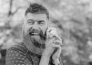 Man with beard and mustache on happy face holds bouquet of dandelions. Romantic hipster made bouquet, green nature