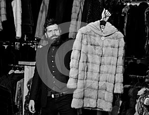 Man with beard and mustache holds coat. Winter clothing concept.