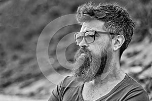 Man with beard and mustache on strict face, nature background, defocused. Bearded man wears modern sunglasses. Hipster