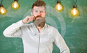 Man with beard and mustache on thoughtful face stand in front of chalkboard. Guy thinking with thoughtful expression
