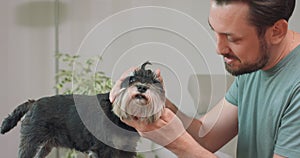 Man with beard and mustashes touches the yorkshire terrier head with his forehead, tilts head back and pets it White