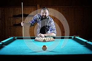 A man with a beard plays a big billiard. Party in a 12-foot pool