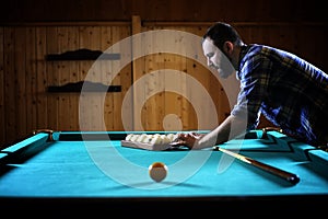 A man with a beard plays a big billiard. Party in a 12-foot pool