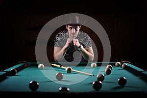 A man with a beard plays a big billiard. Party in a 12-foot pool