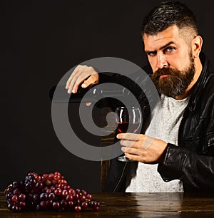 Man with beard pours wine into glass on brown background