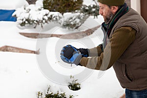 Man with beard sculpts snowball in yard